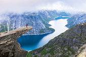 Hiker standing on Trolltunga with panoramic view of lake, Norway